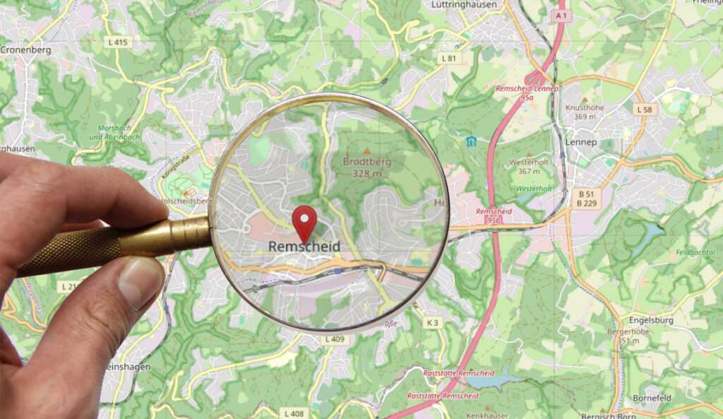 KArte von Resmcheid, darüber hand mit Lupe, Lupe betrachtet Stadtzentrum