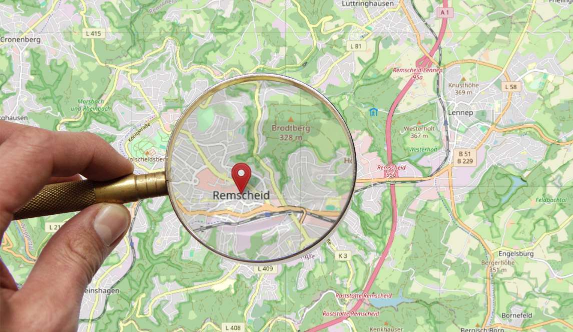 KArte von Resmcheid, darüber hand mit Lupe, Lupe betrachtet Stadtzentrum